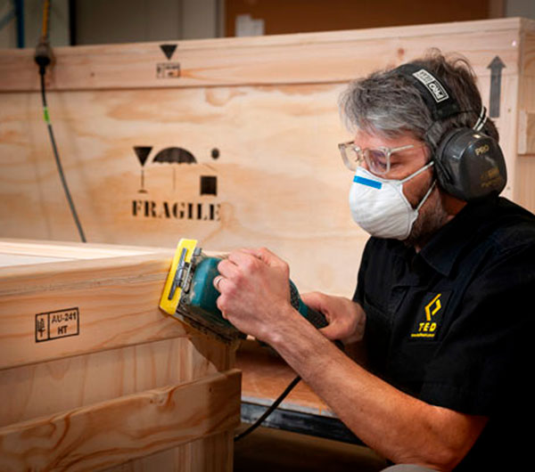 T.E.D. craftsman finishing a fragile-marked timber crate